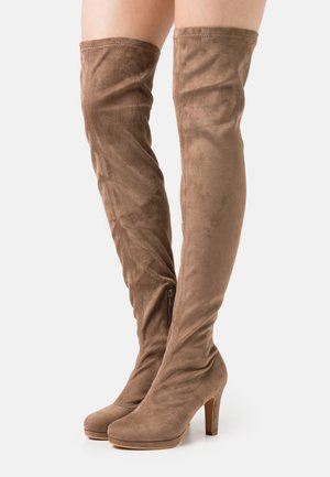 Bottes brunes montantes en daim doux. Dotées d'un bout rond, d'un talon stiletto haut et d'une fermeture éclair sur le côté pour un enfilage facile. Texture lisse.