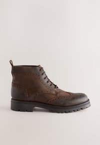 Brauner Leder-Ankle-Boot mit Brogue-Details, sieben Ösen, einer Zuglasche und einer robusten Sohle mit Profil.