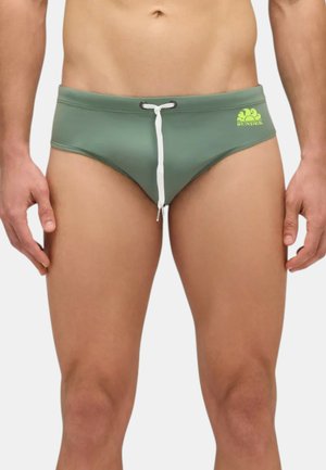 Slip da bagno verde con cordino bianco, dotato di un piccolo logo giallo. Materiale liscio e elasticizzato con un design aderente.