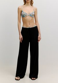 Bloemenpatroon bralette gecombineerd met zwarte, losse sweatpants met een gepatterneerde tailleband en een trekkoord.