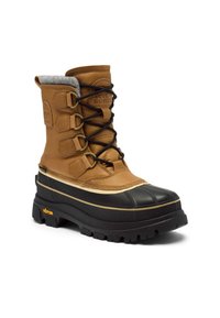 Brun vinterstövel i läder med en robust svart gummisula, snörning och grå fleecematerial vid kragen. Vibram-logotyp synlig.