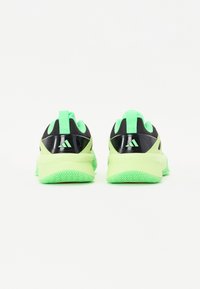 Baskets de sport noires et vert fluo, avec une tige en maille texturée, une semelle épaisse et une languette au talon. Logo Adidas affiché sur les côtés.