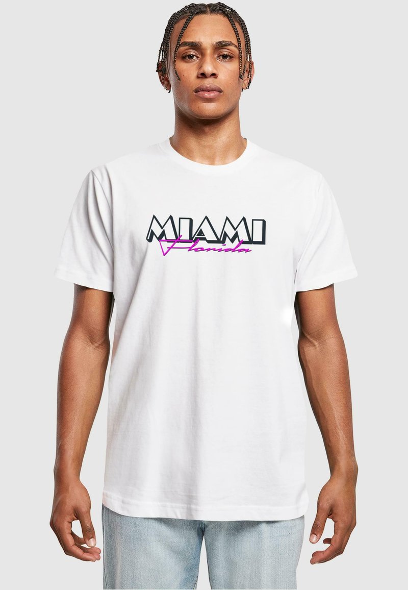 Tricou alb din bumbac cu inscripția "MIAMI" în negru și "Florida" în scris cursiv roz, cu mâneci scurte, guler rotund și o croială relaxată.