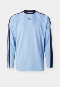 Light blue long-sleeve shirt with black accents and three stripes along sleeves, featuring a small black logo on the chest. Soft fabric texture.
