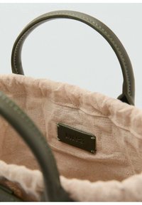 Grüne Lederhandtasche mit einem weichen rosa Innenfutter. Verfügt über ein Etikett mit eingeprägtem "MNG" und robusten, runden Griffen. Texturiertes Stoffinnere.