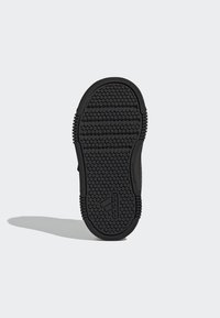 Suola di scarpa in gomma nera con motivo di grip testurizzato, caratterizzata da scanalature orizzontali e verticali e un logo sul lato. Design non marcante.