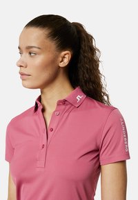 Roze poloshirt van gestructureerde stof, met een kraag, twee knopen en logo-detail op de kraag en mouwen. Korte mouwen.