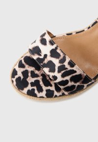 Σανδάλι με λάστιχο σε σχέδιο λεοπάρ, με απαλό υφασμάτινο πάνω μέρος, επίπεδη σόλα και μαξιλαρωμένο πέλμα. Διαθέτει δύο φαρδιές λουριά πάνω από το πόδι.