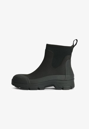 Black ankle boot made of textured rubber, with a reinforced toe, elastic sides, and a pull tab at the back; rugged sole for traction.