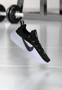 Μαύρο αθλητικό παπούτσι με υφή στο πάνω μέρος, λευκή μεσαία σόλα και μαύρο λογότυπο Swoosh. Διαθέτει κορδόνια και κυκλικό σχέδιο οπών.