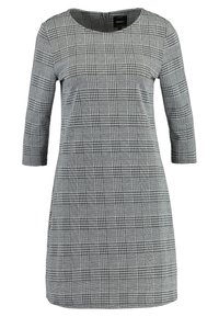 Grå rutmönstrad klänning med trekvartslånga ärmar, rundad halsringning och rak silhuett. Har ett rutig mönster med svarta och vita nyanser.