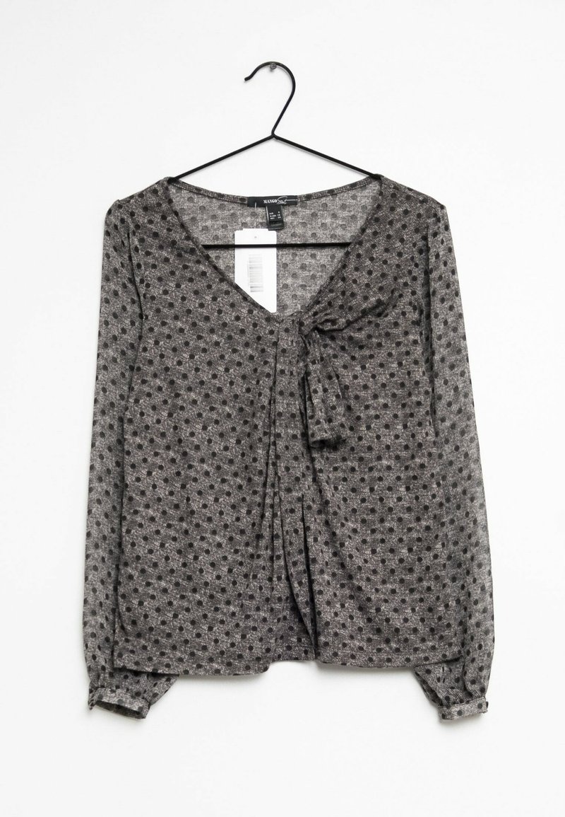 Blusa gris de manga larga con escote en V y lazo frontal. Presenta un estampado de lunares y puños elásticos. Está hecha de una tela ligera y texturizada.
