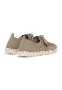 Paar beige Slipper mit gewebtem Zehen-Detail, dekorativer Schleife und dicken weißen profilierten Sohlen, aus der hinteren Perspektive gezeigt.