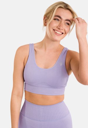 Bralette sportivo lilla con texture a coste, spalline larghe e finitura liscia. Presenta un collo arrotondato e un discreto dettaglio del logo.