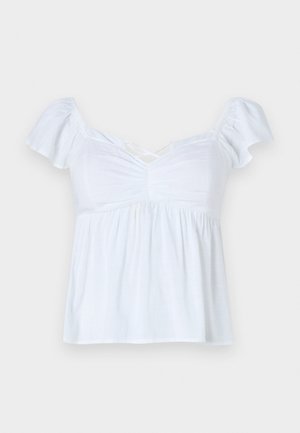 Blusa blanca con mangas cortas abullonadas, detalles fruncidos en la parte delantera y un dobladillo acampanado. Hecha de un tejido ligero, tiene un corte holgado y un escote cruzado.