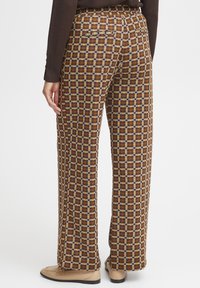 Pantalons larges à motifs marron avec un design en grille jaune moutarde et crème. Confectionnés avec une texture lisse et une coupe confortable.