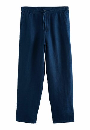 Hand ruht neben marineblauer Hose mit sichtbarer Gesäßtasche, zeigt Stoffstruktur und Nähdetails.