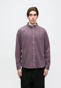 Hnedý kordurový gombíkový košeľový vrch v tlmených fialových odtieňoch, s klasickým golierom, dlhými rukávmi a viditeľnou vertikálnou ribovanou textúrou. Jednoduché biele gombíky.