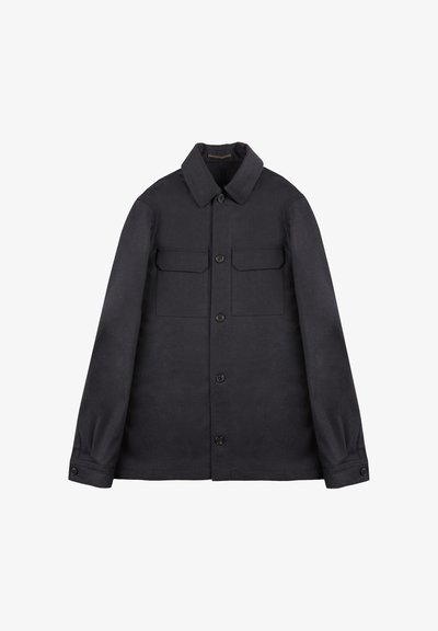 Giacca button-up blu scuro realizzata in tessuto spesso, con colletto, due tasche sul petto e polsini con bottoni. Design minimalista.