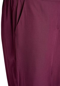 Pantalón de tela burdeos que muestra una textura suave, con un diseño plisado y detalles de bolsillos laterales. El corte entallado realza la silueta.