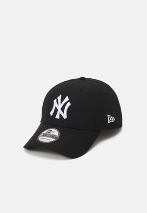 Musta lippalakki, jossa on valkoinen brodeerattu New York Yankees -logo. Varustettu kaarevalla lippareunalla ja takana muovilla säädettävällä vyöllä.
