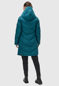 Teal puffer coat with a large hood, shoulder seams, and vertical quilted detailing. Finished with a brown logo tag near the hem.