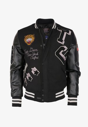 Černá univerzitní bunda s koženými rukávy, nášivkou s hlavou tygra, textem „Top Gun New York Crafted“, hvězdnými nášivkami a proužkovanými manžetami a límcem.