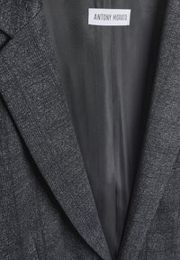 Sivi sako od teksturiranog materijala, s reverima i oznakom "ANTONY MORATO" unutra. Jednostavan dizajn, uski kroj.