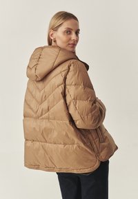 Smeđa puf jakna s kapuljačom, s quiltanim uzorkom i kopčom na snap, prikazana sa stražnje strane na neutralnoj pozadini.