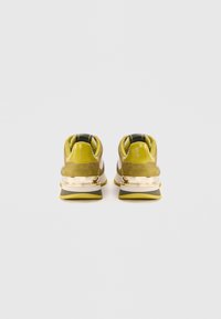 Groene suede sneakers met een strak ontwerp, metallic gouden accenten en eengepatrooneerde stoffen binnenkant. Afgeronde hak met textuur op de buitenzool.