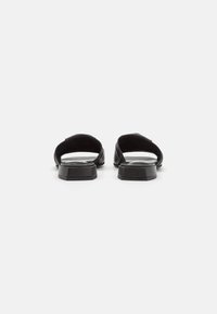 Svarta slidesandaler med öppen baksida, slät läderöverdela, platta sulor och breda remmar för komfort. Minimalistisk design utan dekorativa inslag.