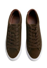 Hnědé semišové tenisky s bílými gumovými podrážkami, které mají kulaté šněrování, texturovaný povrch a hnědý textilní akcent na patě.