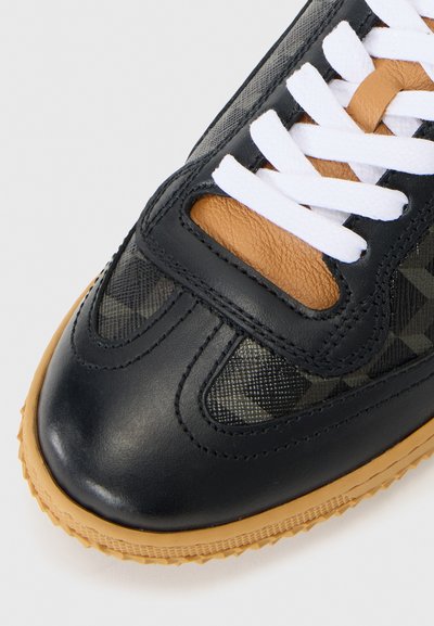 Sneaker in pelle nera con accenti in rete, lacci bianchi e suola in gomma naturale. Presenta un design testurizzato sulla punta e sui pannelli laterali.