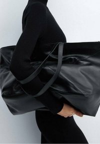 Sac fourre-tout en cuir noir avec une texture lisse, de grande taille et deux poignées pour l'épaule. Il présente un design minimaliste et une forme angulaire.