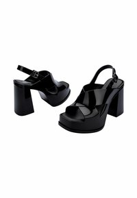 Sandales à plateforme noires avec une finition brillante, dotées d'un design à brides croisées, d'une boucle arrière et de talons épais.