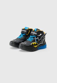 Sorte høy-toppsko med blå snøring, prydet med Batman-grafikk og logo. Gule detaljer og gjennomskinnelig blå såle gir ekstra stil. Geox-merket.
