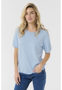 Pull bleu clair à manches courtes avec une texture à pois surélevés, col rond et coupe décontractée. Associé à un jean bleu ajusté. Design simple.