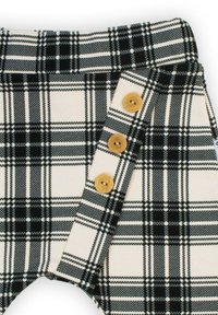 Czarno-białe spodnie w kratę wykonane z miękkiego materiału, z wysokim stanem i trzema drewnianymi guzikami po bokach.