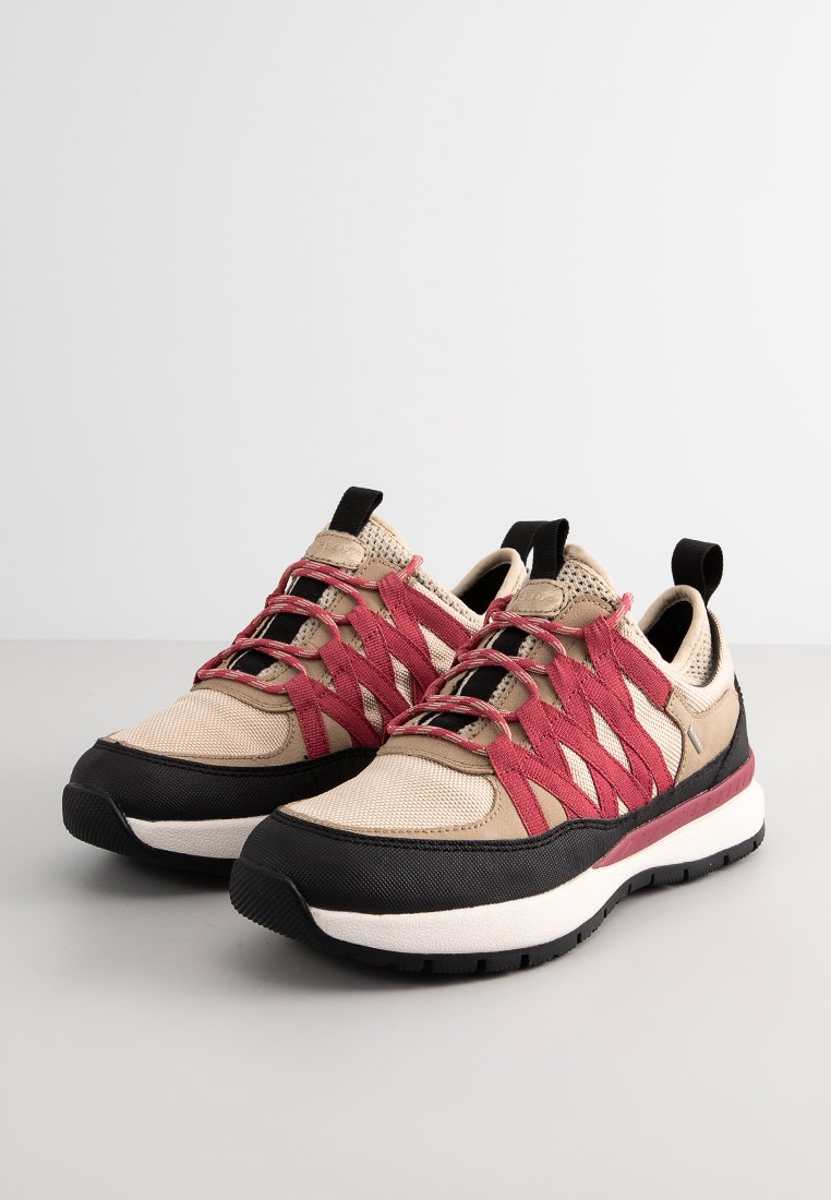 Beżowe buty sportowe z czerwonymi elastycznymi sznurowadłami, czarną gumową podeszwą i teksturowaną siateczką na cholewce. Posiadają uchwyt i wyrazisty akcent śródpodeszwy.