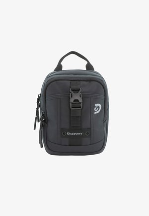 Zaino in tessuto nero di forma rettangolare, dotato di manico superiore, chiusura con zip, fibbia frontale e dettaglio del logo. Due tasche con zip in vista.