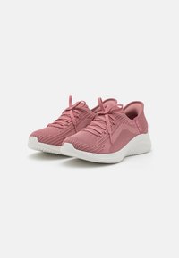 Pink athletic shoes made of breathable knit fabric with textured pattern, round toe, flat white rubber sole, and matching laces.