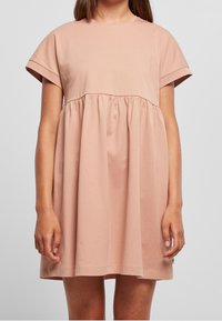 Kurzes, pastellrosa Kleid mit gerafftem Taillenband, Rundhalsausschnitt und weichem Baumwollstoff. Fließende Silhouette, die über dem Knie endet.