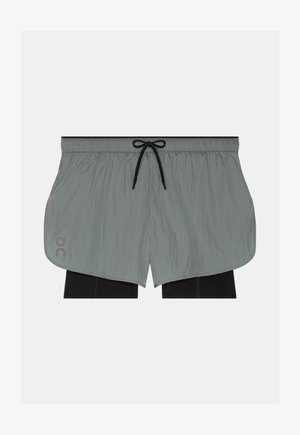 Shorts à taille élastique grise avec leggings de compression intérieurs noirs et cordon noir sur un fond uni.
