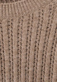 Sweter z dzianiny w jasnobrązowym kolorze o prążkowanej fakturze. Posiada ażurowy wzór i okrągły dekolt. Miękki materiał z widocznymi włóknami.