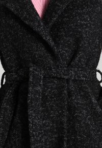 Cappotto in misto lana nero con finitura testurizzata, caratterizzato da un ampio colletto, design avvolgente e cintura in tessuto per la chiusura.