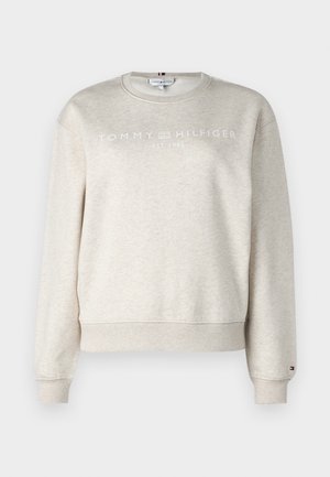 Felpa in cotone beige con maniche lunghe, polsini e orlo a coste. Presenta il logo bianco "TOMMY HILFIGER EST. 1985" sul petto. Vestibilità classica.