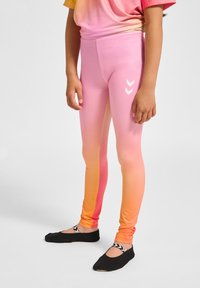 Roze en oranje gradient leggings met een gladde textuur en witte chevronaccenten. Gecombineerd met zwarte instapschoenen met een gestreepte band.