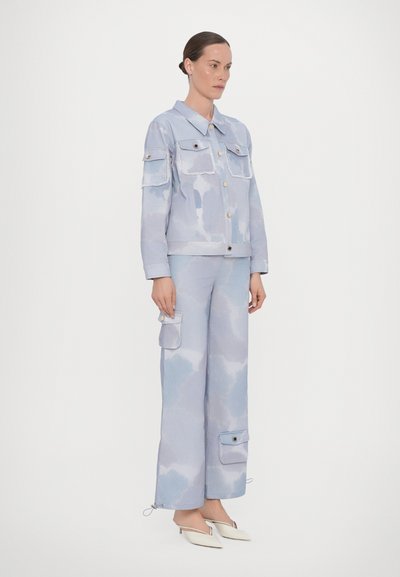 Lyseblå denimjakke med to brystlommer og knaplukning, parret med matchende løstsiddende bukser med sidelommer og lynlåse.