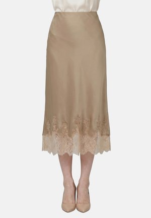 Beiger Satin-Midirock mit Spitzenbesatz am Saum, getragen mit hautfarbenen High Heels und einer in die Hose gesteckten weißen Bluse.