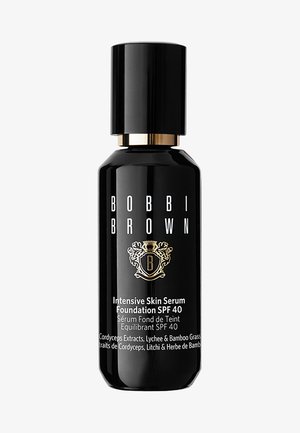 Svart sylinderformet flaske med et lokk i gullfarge, merket "Bobbi Brown Intensive Skin Serum Foundation SPF 40" med dekorativ logo og tekst.